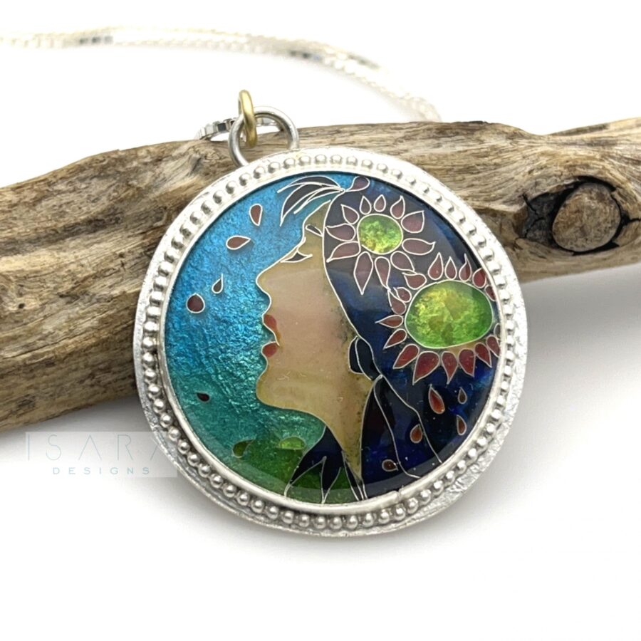 Cloissone enamel pendant of a woman with flowers in her hair. This colorful enamel piece is set in sterling silver and makes a beautiful necklace.