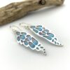 Plique-a-jour enamel and silver dangle earrings shaped like wings and made of silver with holes cut out and then filled with blue and hot pink enamel